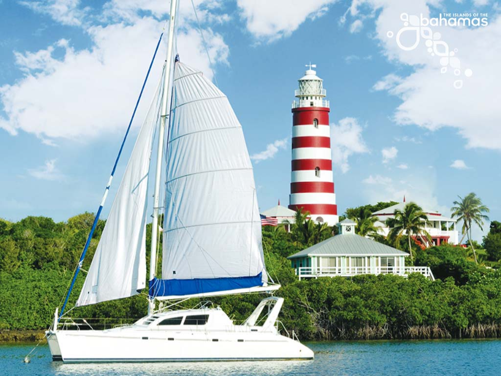 A sailboat on the water with a red and white striped lighthouse in the background.